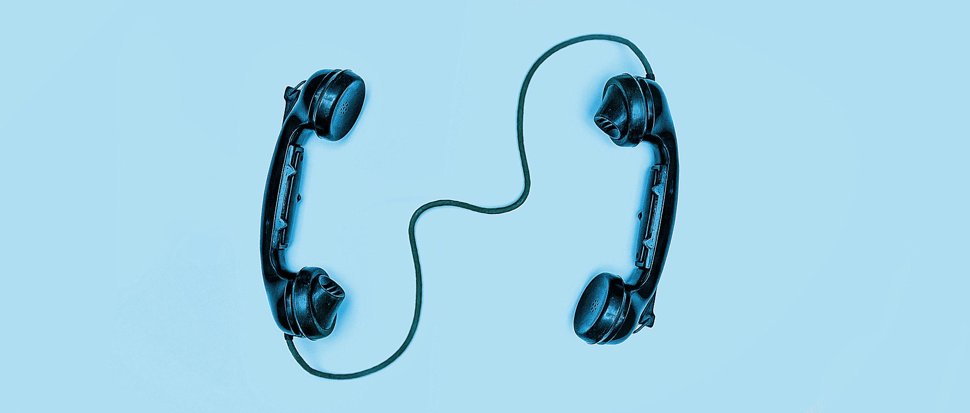 Two old-fashioned phone headsets are attached to each other with a cord.