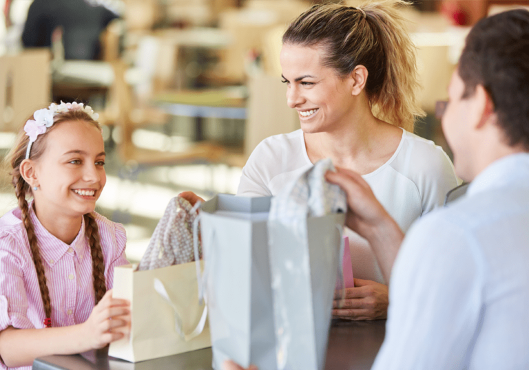 Mom and daughter at a department store while they smile and chat with a cashier