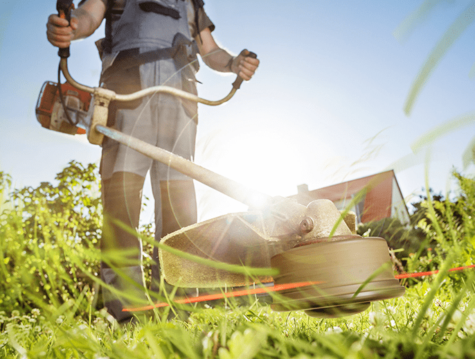 person using a brush cutter on a lawn